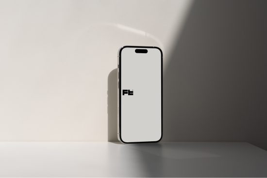 Minimalist smartphone mockup standing against a wall with shadow, ideal for showcasing mobile app and web design.